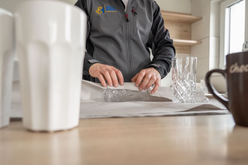 Ein Mitarbeiter von John & Martin wickelt ein Glas in Packseide.
